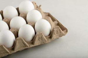 Huevos de gallina cruda en una caja de huevos sobre un fondo blanco. foto