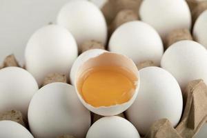 Huevos de gallina cruda en una caja de huevos sobre un fondo blanco. foto