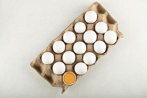 Raw chicken eggs in an egg box on a white background photo