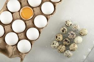 huevos de gallina crudos en un recipiente de cartón y huevos de codorniz foto