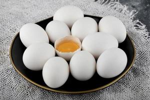 White eggs and yolk on a black plate photo