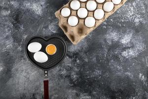 Pan and container of eggs on a marble background photo