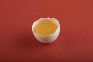 Broken organic egg on a red background photo