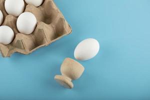 Container of fresh eggs on blue background photo