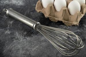 Huevos blancos en un recipiente de cartón y un bigote sobre un fondo de mármol foto