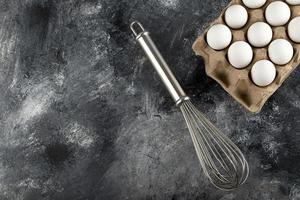 White eggs in a carton container and a whisker on a marble background photo