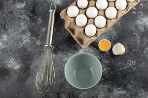 White eggs in a carton container and a whisker on a marble background photo