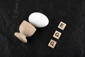 Single egg and wooden letters spelling Egg on a black background photo