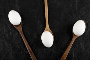 huevos blancos crudos en cucharas de madera foto