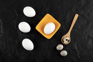 Quail eggs and chicken eggs on a black background photo