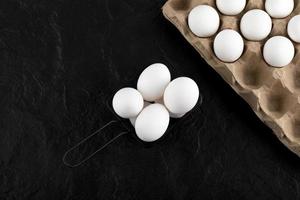 Carton of white eggs on a black background photo