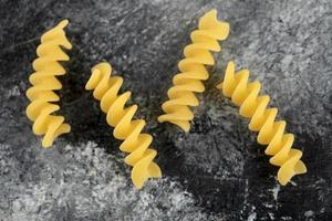 Raw fusilli pasta on a marble background photo