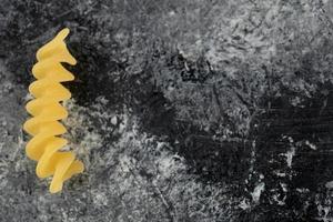 Single raw fusilli pasta on a marble background photo