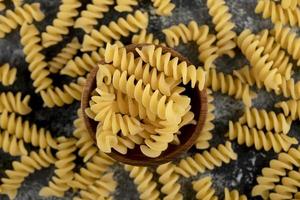 Bowl of raw fusilli pasta on a marble background photo