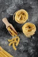 Tagliatelle nests and fusilli on a marble background photo