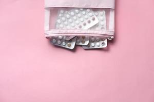 Pastillas anticonceptivas sobre fondo rosa foto