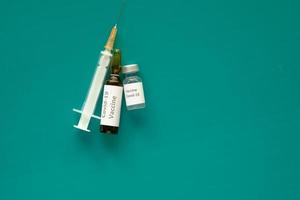 Close up of coronavirus vaccine and syringe on green background photo