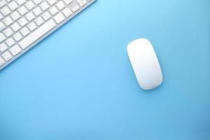 Top view of computer mouse and keyboard on blue background photo