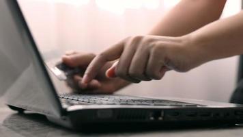 close-up de mãos femininas segurando um cartão de crédito e fazendo uma compra usando um laptop. video