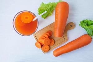 Top view of fresh carrot juice on a white table photo