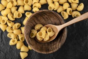 A wooden spoon of uncooked conchiglie macaroni photo
