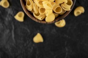 Italian uncooked pasta conchiglie in a wooden bowl photo