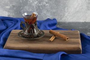 A glass tea with cinnamon sticks on a wooden cutting board photo