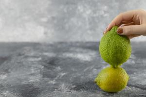mano de mujer sosteniendo dos limones frescos verdes