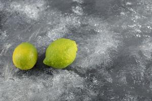 Dos limones frescos verdes sobre un fondo de mármol