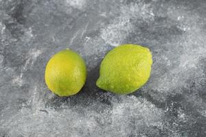 Dos limones frescos verdes sobre un fondo de mármol