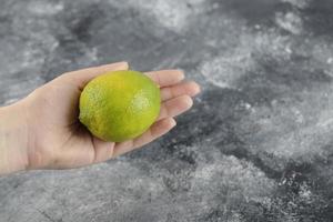 mano de mujer sosteniendo un limón verde fresco foto