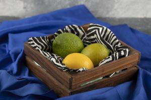 A wooden basket with three lemons on a blue cloth photo