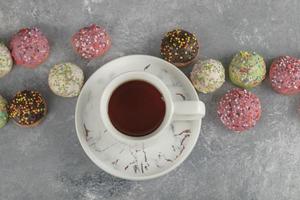 donas dulces de colores con una taza de té foto