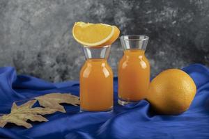 Two glass pitchers with delicious juice and sliced orange fruit
