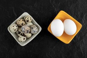 Tres huevos de codorniz y huevos de gallina sobre un fondo negro foto