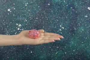 Woman's hand holding a small pink doughnut