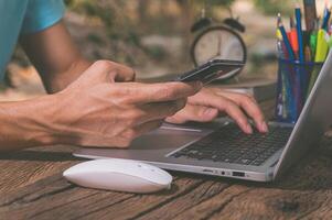 Man using laptop and mobile phone on wooden table photo