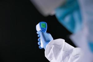 Hand holding infrared thermometer on black background