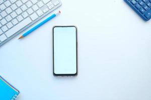 Top view of smart phone and office stationary on white background photo