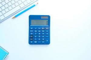 Cerca de la calculadora y el teclado azul sobre fondo blanco. foto