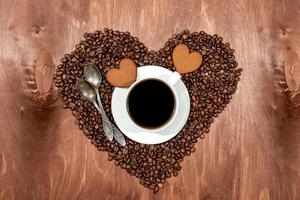 taza de café con leche, pan de jengibre en forma de corazón y dos cucharas en un corazón foto