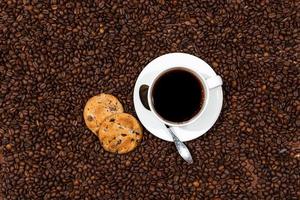Taza de café con leche y galletas en el fondo de los granos de café foto