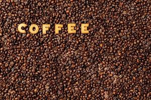The word COFFEE made from biscuit letters on a dark coffee bean background photo