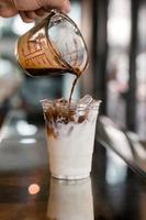 barista vertiendo espresso en un vaso de café helado foto