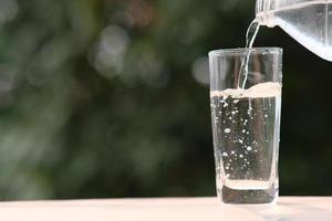 Agua potable mineral en la mesa de madera y agua en vidrio foto