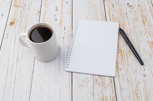 Coffee and a notebook with a pen on a wooden desk photo