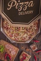 pizza con mozzarella, chorizo calabrese, pimiento verde, cebolla y pimiento calabrese en caja de entrega