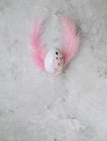 Easter painted eggs and pink feathers on a marble background