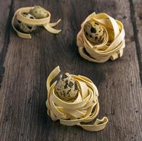 Quail eggs in pasta nests on a wooden background photo