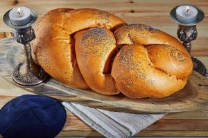 Shabbat challah on a wooden stand, with candles and a rustic bale photo